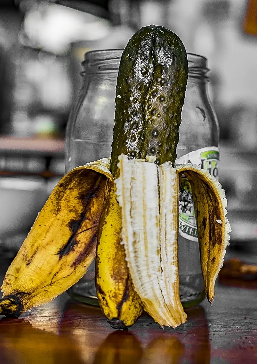 Pickle standing inside a peeled banana peel in front of a glass jar